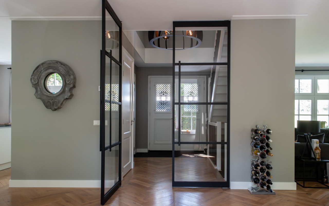 Strakke stalen taatsdeuren tussen hal en woongedeelte